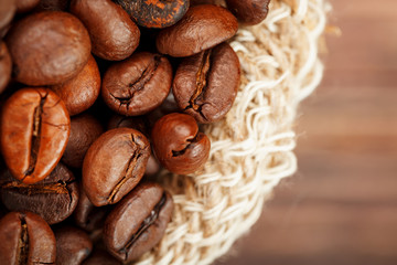 Coffee beans closeup in burlap bag on wooden background.