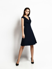 Young beautiful woman posing in new fashion long casual dark black winter dress happy smiling walking full body