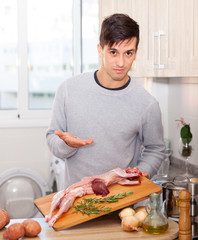 Man holding lamb carcass in domestic kitchen