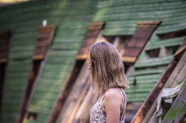 A woman in a dress stands in the background of an old abandoned dilapidated house