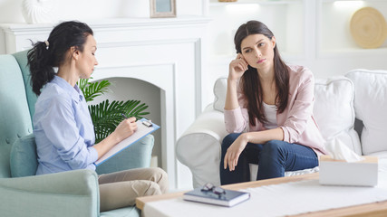 Unhappy woman visiting private psychotherapist at her private clinic