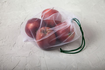 Apples, food in an eco bag on a light background. View from above. Zero waste.