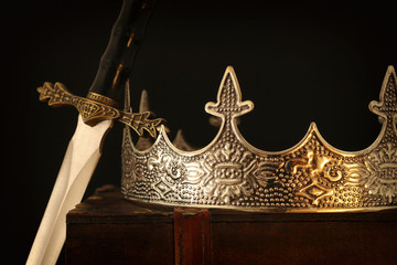 low key image of beautiful queen/king crown over antique box next to sword. fantasy medieval...