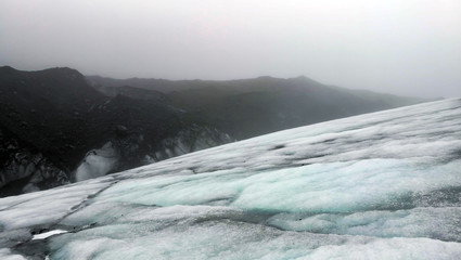 Overcast weather glacier hiking in Iceland volcanic black stone landscape with ice and snow