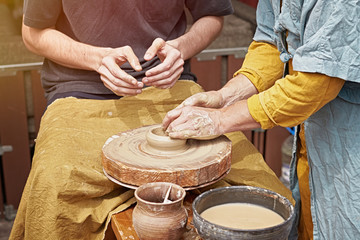 The teacher teaches the student how to make simple clay products