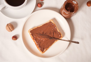 Bread toast with chocolate cream butter, jar of chocolate cream on the white background. Top view.