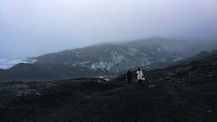 Fototapeta na wymiar Overcast weather glacier hiking in Iceland volcanic black stone landscape with ice and snow