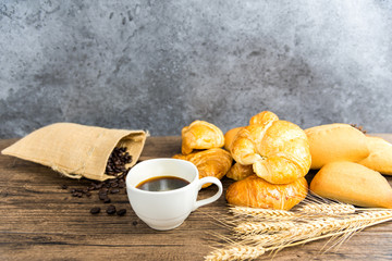 Black coffee in white glass placed on a wooden table. Have coffee beans in a bag. Toasted bread and wheat Have breakfast before work.