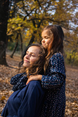 Daughter little girl hugs her mother in the forest or park. Family relationships concept