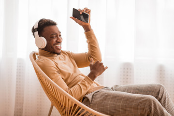Fototapeta na wymiar Positive Man Singing Listening To Music Wearing Headphones Sitting Indoor