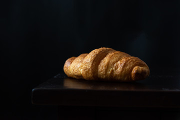 Close Up of Fresh Baked Croissant on wood table with Coffee Mug and  news paper on Relaxing Morning at Home, Bread and coffee, breakfast Healthy food of the city life