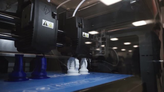 Two 3D printer heads simultaneously produce chess pieces.1920X1080 Full Hd.