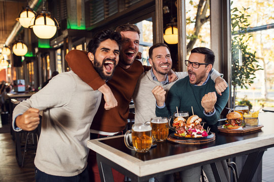 Friends watching sport match in beer pub