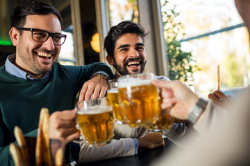 Group of happy friends drinking beer in pub