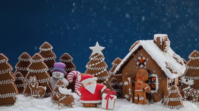 Gingerbread house christmas fir trees Santa Claus and gift cookies under falling snow winter holiday celebration concept