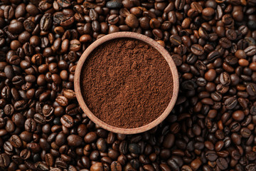 Textured background of coffee beans with bowl of powder, close up