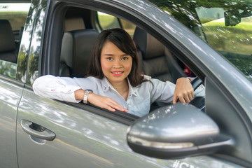 Cute Asian girl inside the car smiling and looking at the camera