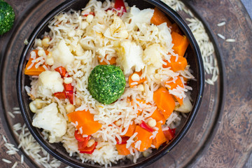Colorful long basmati rice with vegetables in bowl with spinach green ball. Vegan or vegetarian healthy food.