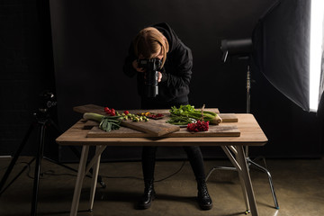 female photographer making food composition for commercial photography and taking photo on digital...