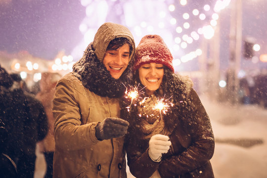 Joyful Couple Holding Bengal Lights Sparklers Celebrating New Year Outside