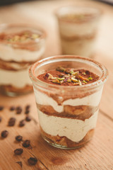 Tiramisu with pistachios and coffee in jars on a wooden countertop