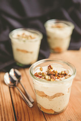 Tiramisu with pistachios and coffee in jars on a wooden countertop