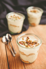 Tiramisu with pistachios and coffee in jars on a wooden countertop