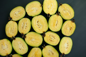 Pieces of feijoa on a black background. feijoa - the fruit crop of the tropical regions, agave. healthy food concept, eco-friendly, vegetarian, raw, organic, Tropical abstract background.