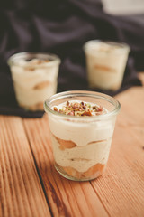 Tiramisu with pistachios and coffee in jars on a wooden countertop