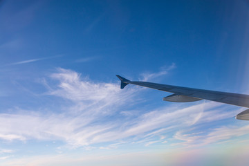 Flying into blue sky and sea of clouds and Wing of airplane with skyline  top view as look from window airplane, during flight space for  text message, frame or traveling idea concept