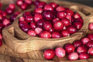 fresh cranberries in a wooden bowl close-up view from above. background with fresh ripe cranberries.