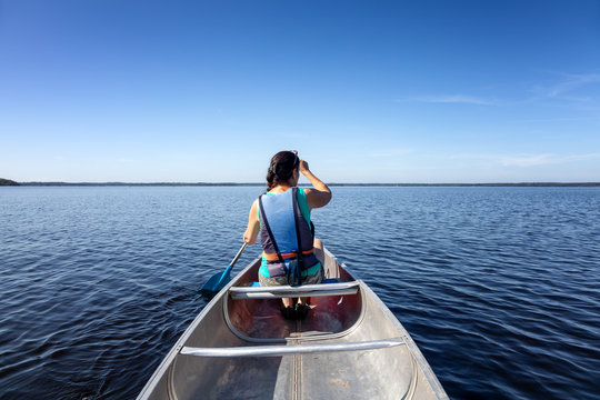 Sportliche Frau mit einem Kanu auf einem See in Schweden