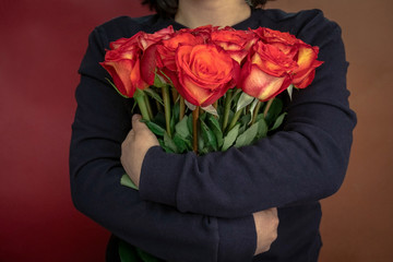 young woman in a black jacket embraces a bouquet of large roses