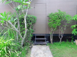 the back door of brown home with small stair and green trees at the both two side