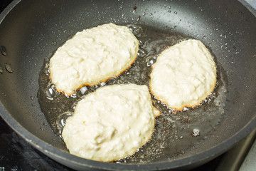White curd cheese cakes fried in oil pan.