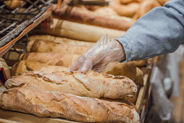 A young woman takes from the counter in the supermarket fresh bread .