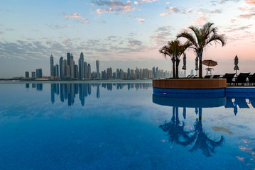 Beautiful swimming pool on Dubai skyline background with reflections in the water