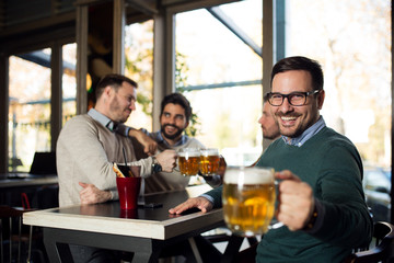 Handsome man holding glass of beer in pub