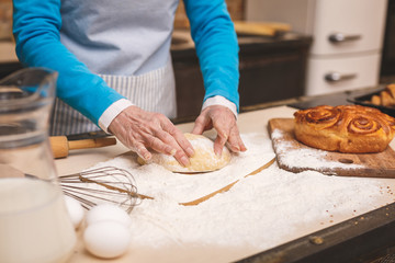 Close-up portrait of attractive smiling happy senior aged woman is cooking on kitchen. Grandmother making tasty baking.