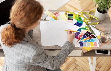 Seamstress working in atelier, drawing new sketches