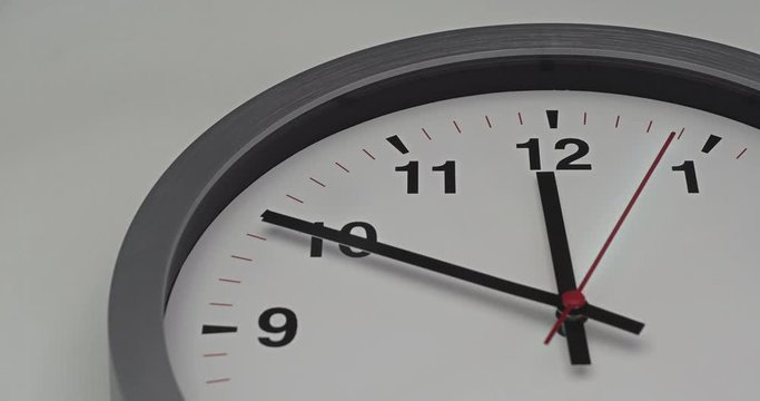 Truck shot of time-lapse gray clock with black arrows shows motion the time speed up from 11.00 p.m. and slow down to 12.00 p.m., How time flies concept.