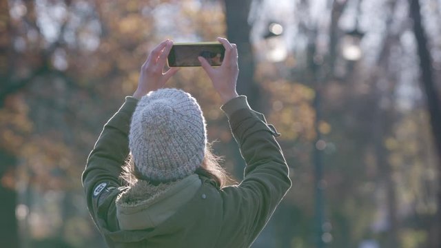 Young woman taking pictures with smartphone in the forest