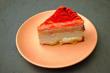 Slice of cake with yogurt cream and soft red icing on a saucer