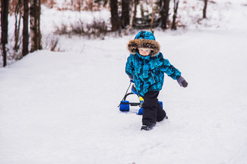Fototapeta na wymiar Boy with snow-scooter on a winter walk.
