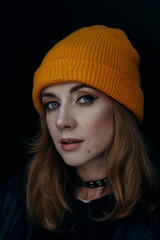 head shot of a confident  beautiful caucasian woman in a yellow hat on a black background