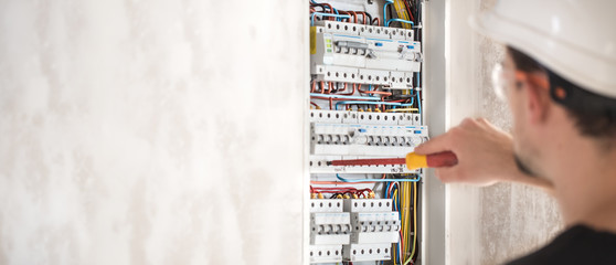 Man, an electrical technician working in a switchboard with fuses. Installation and connection of...