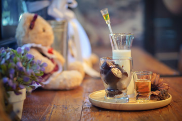 Choosing Focus: An ice heart latte is on a plate, try to place on a table, counter, and there is a teddy bear nearby in a warm atmosphere