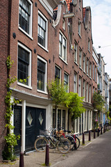 Fototapeta na wymiar View of parked bicycles in front of historical, traditional and typical buildings showing Dutch architectural style in neighborhood called Jordaan in Amsterdam.