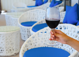 A woman's hand holds a glass of chilled red wine. The concept of wine tasting