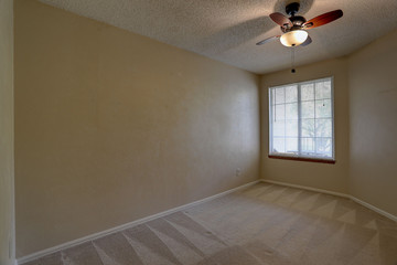 Vacant, carpeted bedroom with ceiling fan in condominium apartment complex